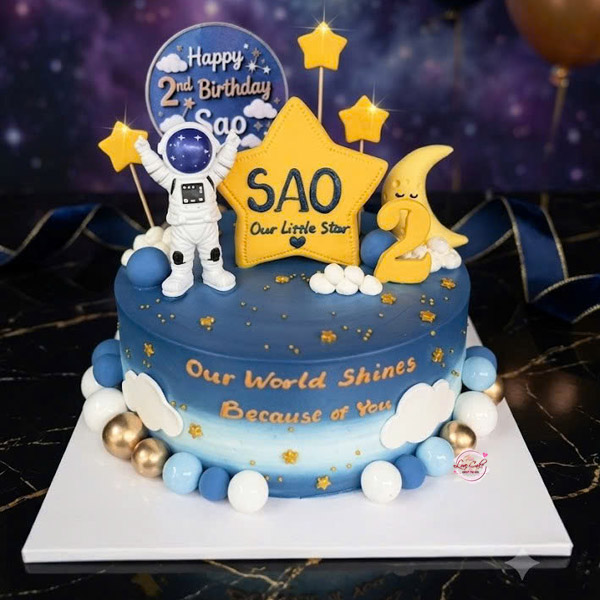 Bánh sinh nhật trang trí phi hành gia tông xanh vũ trụ cho bé trai 2 tuổi với mô hình phi hành gia, ngôi sao và mặt trăng.